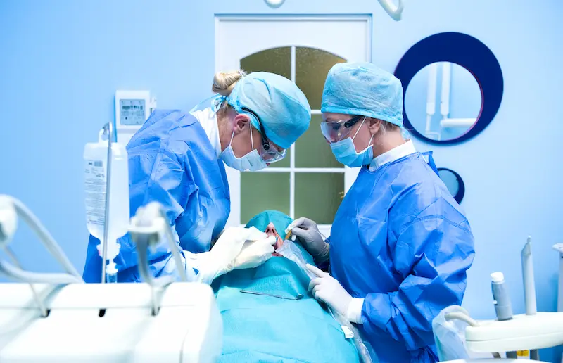 Two dentists performing dental implant surgery.