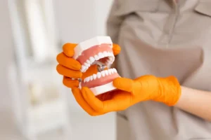 A dental assistant holds a pair of dentures, which are less secure than dental implants.
