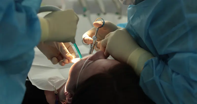 A dental implant specialist administers local anesthesia to a patient.
