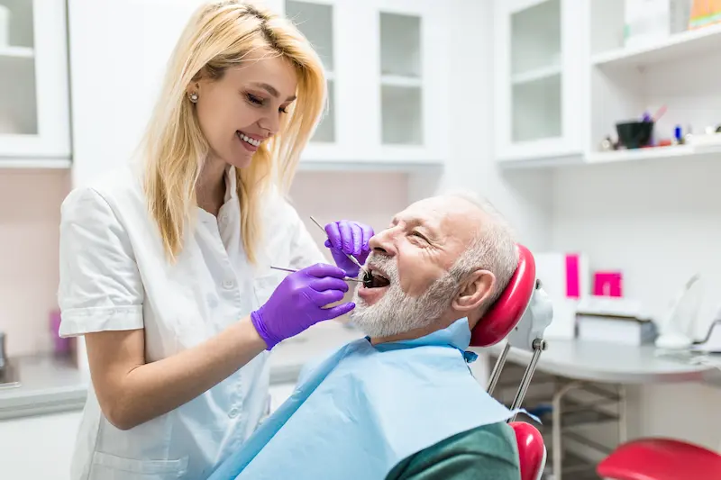 A dental hygienist checks a tooth replacement for a senior patient.